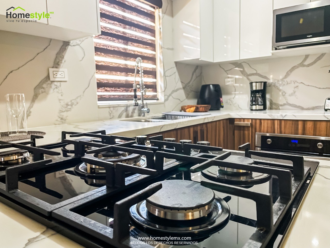 Cocina en forma de L con barra-comedor y cascada. Diseñada en melamina Nogal Terracota para gabinetería inferior y MDF Alto Brillo Blanco para gabinetería superior. Cubierta y Backsplash de Cuarzo Corian Calacatta Natura.