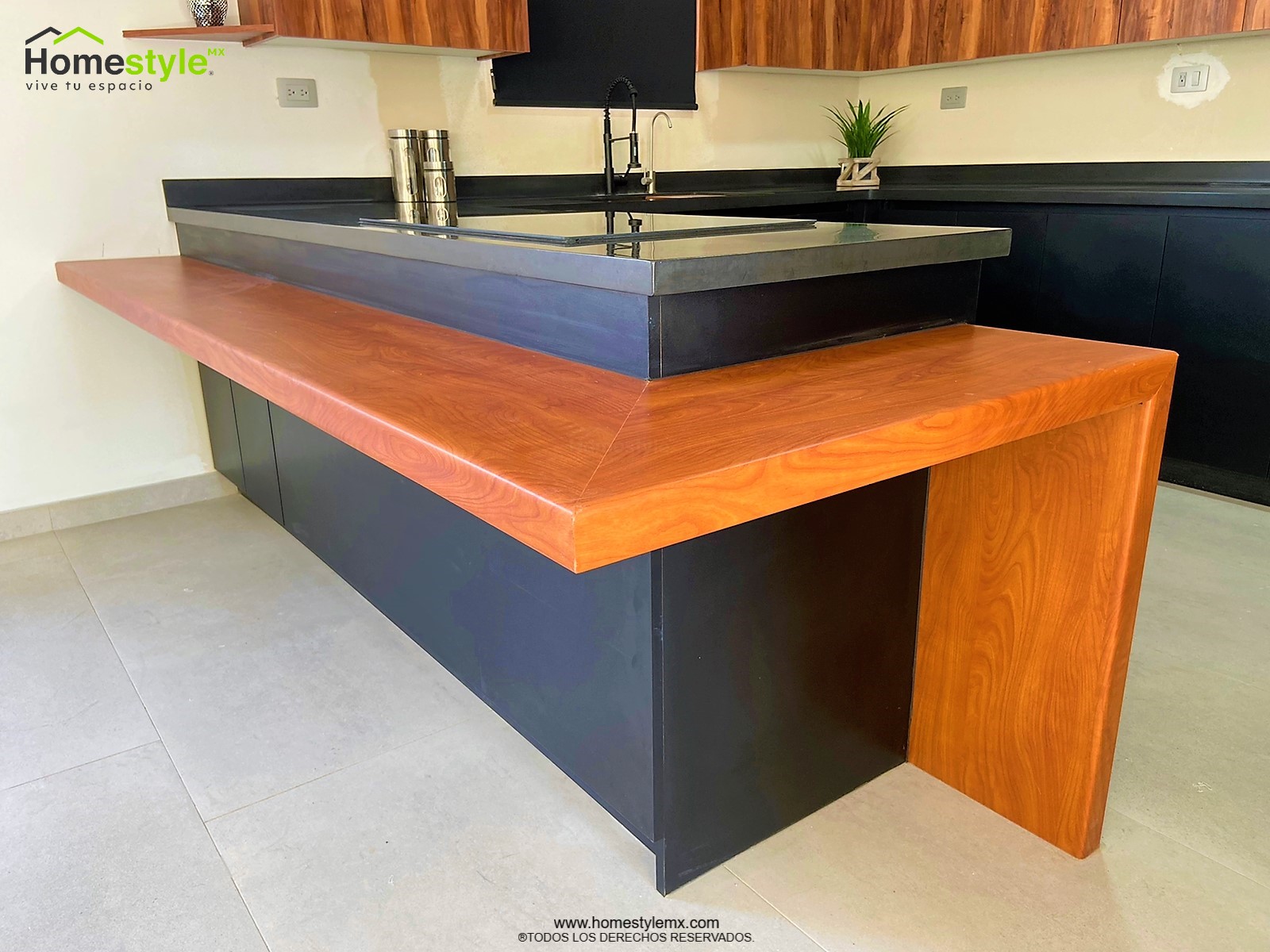 Cocina en forma de J con barra-comedor con estructura, diseñada en Melamina Bestboard Negra para gabinetería inferior y gabinetes sobre walles y Melamina Vesto Cerezo Sierra para gabinetería superior. Puerta de alacena en Melamina Bestboard Negro Mate. Cubierta de cocina de superficie solida Saharan Night y de comedor en Formaica Wild Cherry.