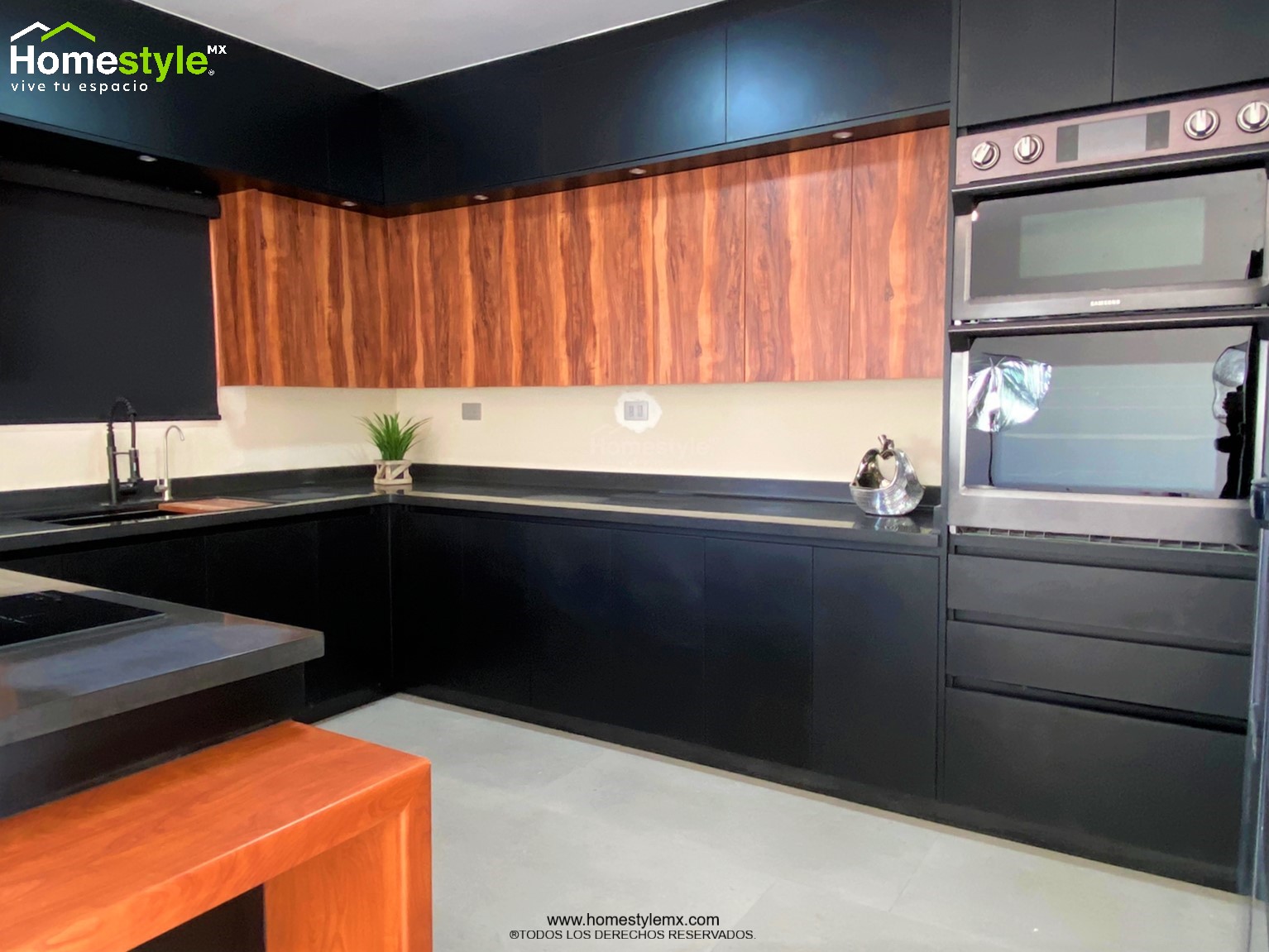 Cocina en forma de J con barra-comedor con estructura, diseñada en Melamina Bestboard Negra para gabinetería inferior y gabinetes sobre walles y Melamina Vesto Cerezo Sierra para gabinetería superior. Puerta de alacena en Melamina Bestboard Negro Mate. Cubierta de cocina de superficie solida Saharan Night y de comedor en Formaica Wild Cherry.