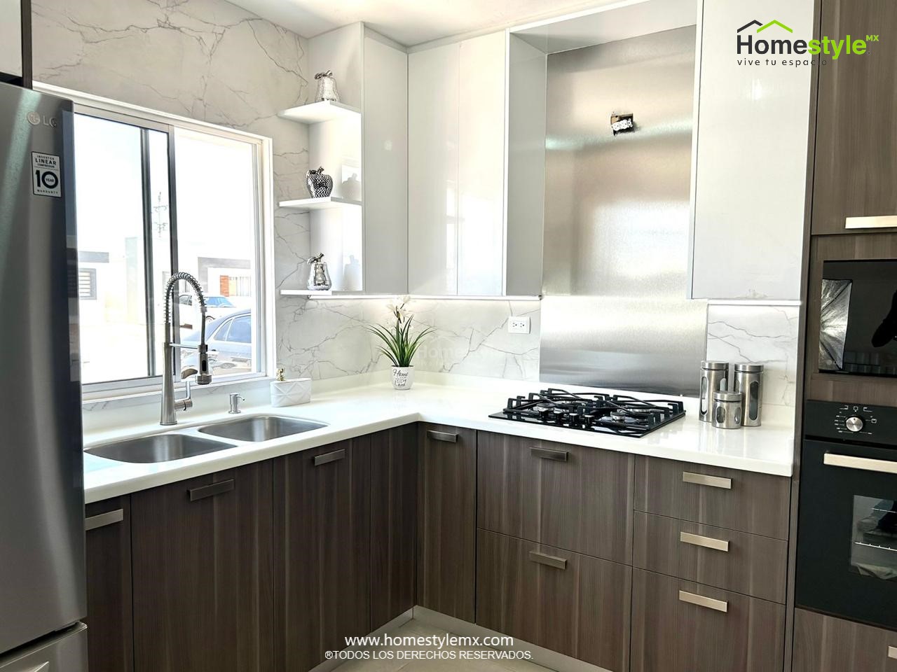 Cocina en forma de L. Diseñada en Melamina Vesto Linosa Ceniza para gabinetería inferior, MDF Alto Brillo Blanco para gabinetes superiores y backsplash de acero inoxidable. Con una cubierta de Superficie Solida Wilsonart Frosty White.