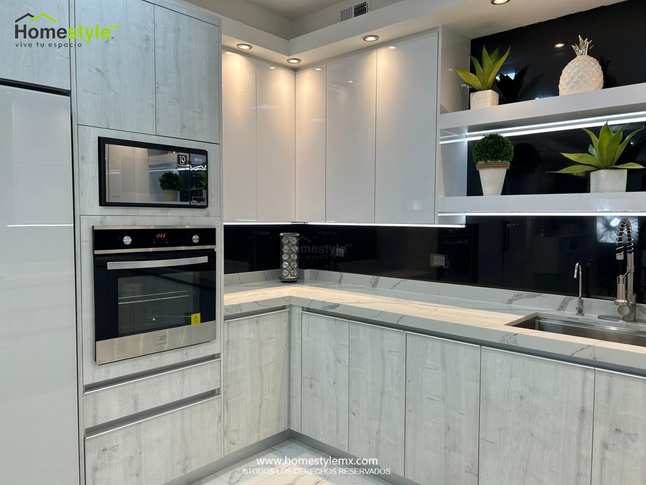 Hermosa cocina en forma de J con barra comedor para 3 personas. Diseñada en Melamina Vesto Alaska para gabinetería inferior, MDF Alto Brillo Blanco para gabinetes superiores y backsplash en MDF Alto Brillo Negro, sistema de iluminación integrada tanto en gabinetes como en cubierta y zoclos. Con una cubierta de Cuarzo Calcutta Marble para la cocina y Superficie Solida Wilsonart Super White para la barra. ✨