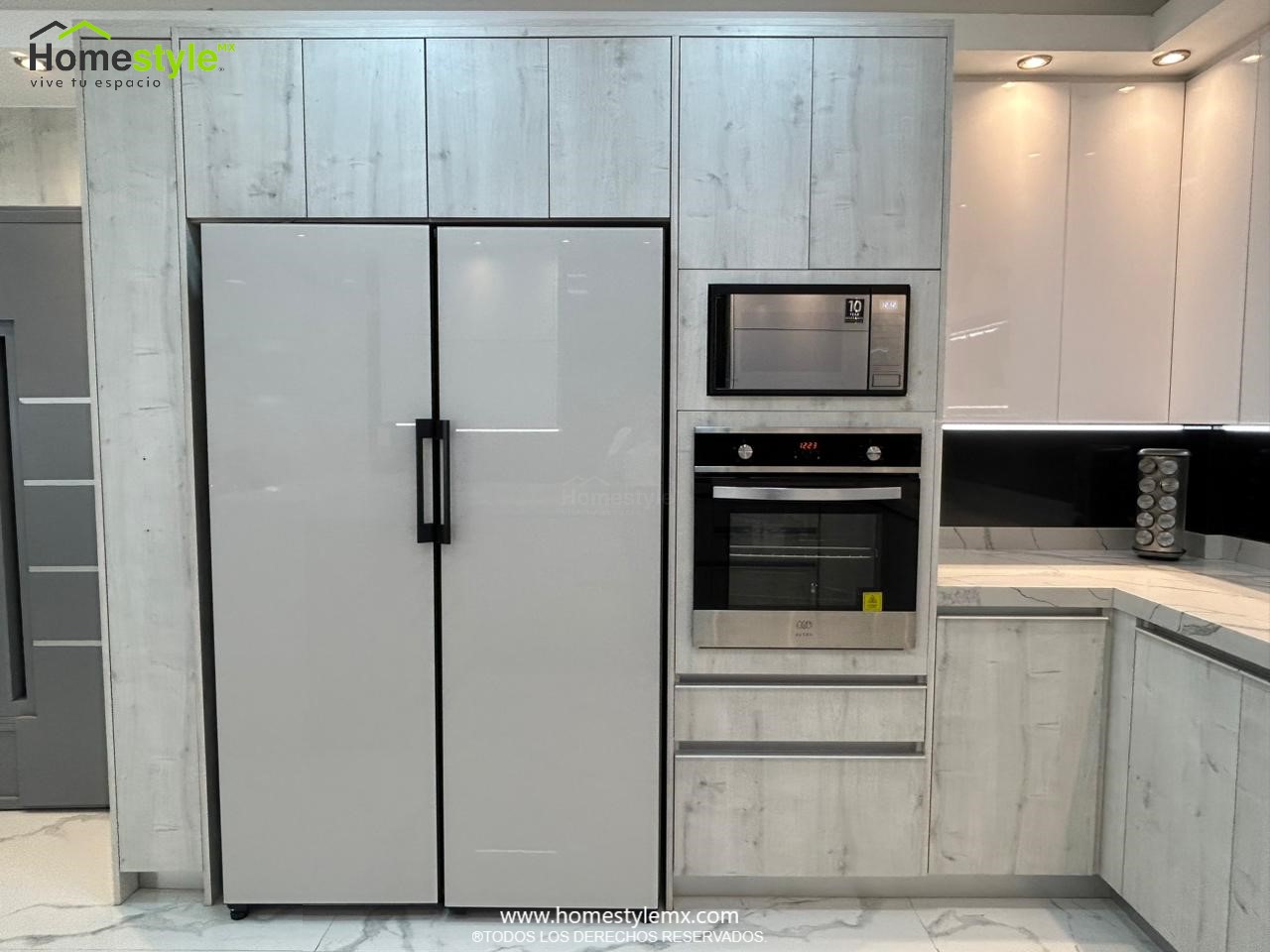 Hermosa cocina en forma de J con barra comedor para 3 personas. Diseñada en Melamina Vesto Alaska para gabinetería inferior, MDF Alto Brillo Blanco para gabinetes superiores y backsplash en MDF Alto Brillo Negro, sistema de iluminación integrada tanto en gabinetes como en cubierta y zoclos. Con una cubierta de Cuarzo Calcutta Marble para la cocina y Superficie Solida Wilsonart Super White para la barra. ✨