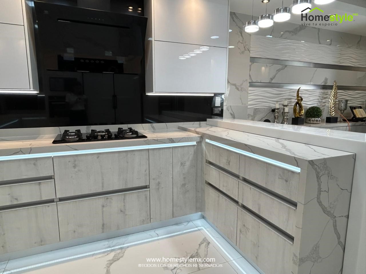 Hermosa cocina en forma de J con barra comedor para 3 personas. Diseñada en Melamina Vesto Alaska para gabinetería inferior, MDF Alto Brillo Blanco para gabinetes superiores y backsplash en MDF Alto Brillo Negro, sistema de iluminación integrada tanto en gabinetes como en cubierta y zoclos. Con una cubierta de Cuarzo Calcutta Marble para la cocina y Superficie Solida Wilsonart Super White para la barra. ✨