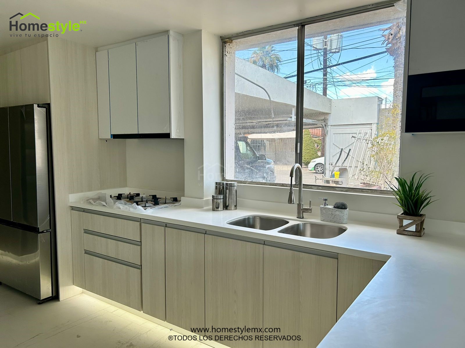 Cocina en forma de J. Diseñada en Melamina Teka para la gabinetería inferior y MDF Alto Brillo Blanco para gabinetería superior. Detalles en melamina Negra y Lambrín Cedro. Con una cubierta de Superficie Solida.