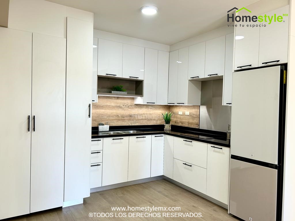 Cocina en forma de L. Diseñada en Melamina Blanca y MDF Alto Brillo Blanco. Con una cubierta de superficie solida Deep Nocturne.