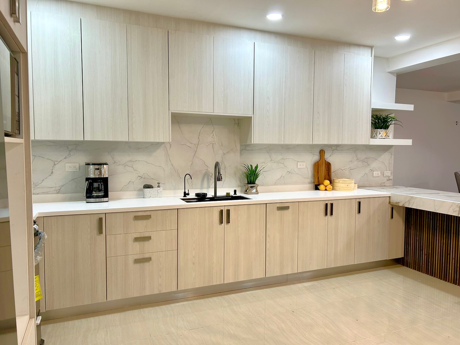 Cocina en forma de L. Diseñada en Melamina Teka Ártico para la gabinetería, Melamina Blanca para repisas, Melamina Marmara y acero inoxidable para backsplash.