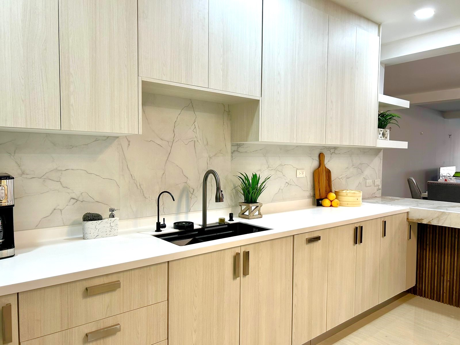 Cocina en forma de L. Diseñada en Melamina Teka Ártico para la gabinetería, Melamina Blanca para repisas, Melamina Marmara y acero inoxidable para backsplash.