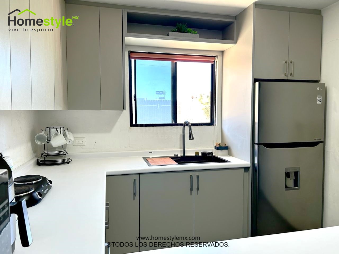 Cocina en forma de J con barra comedor. Diseñada en Melamina Gris para gabinetes inferiores y Melamina Blanca para gabinetería superior. Con una cubierta de Formaica Designer White.