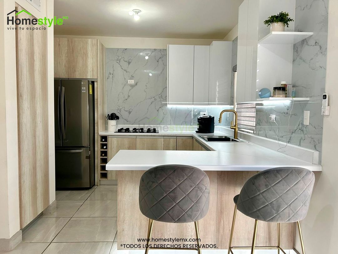 Cocina en forma de L con barra comedor y área de alacena. Diseñada en Melamina Toscana para gabinetes inferiores y MDF Alto Brillo Blanco para gabinetería superior. Con una cubierta de Formaica Blanca. Backsplash de Laminado de PVC Marmoleado Blanco.