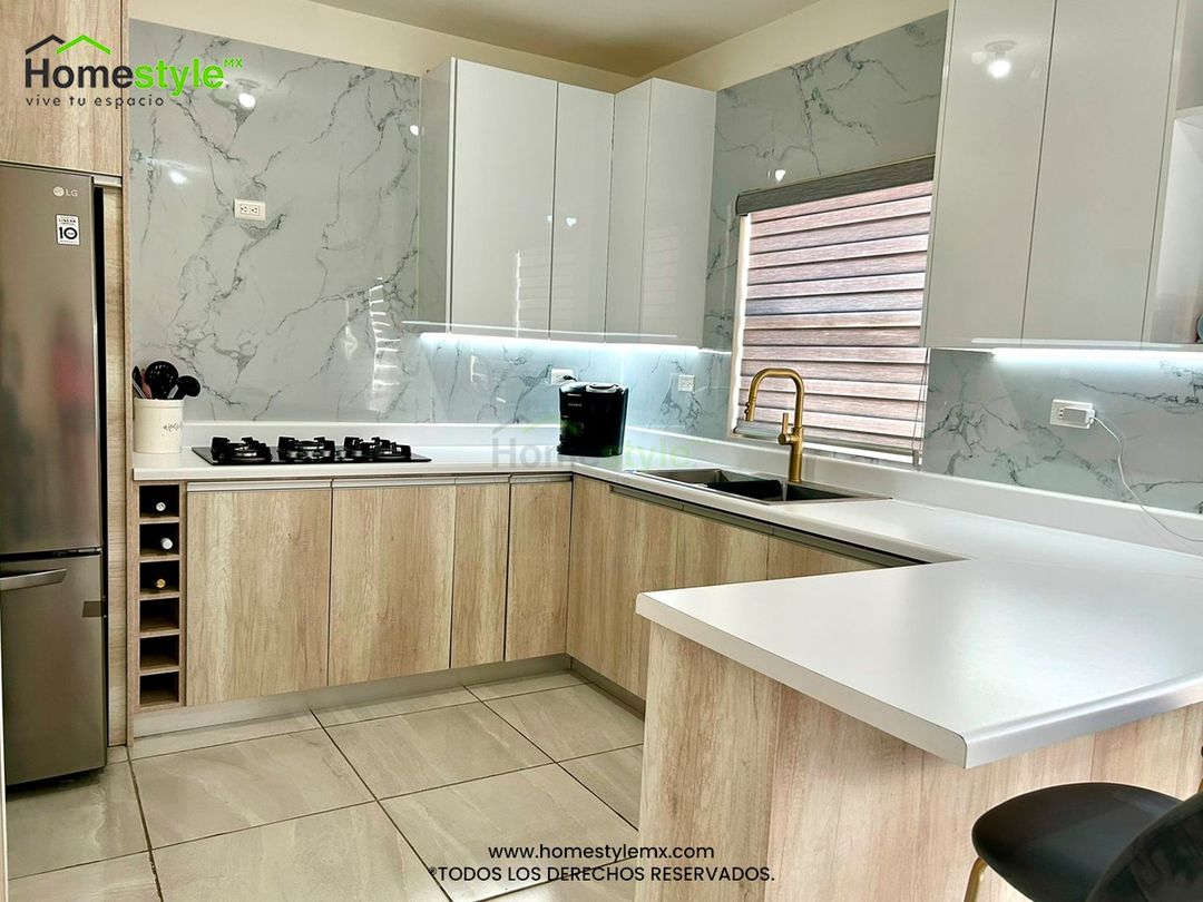 Cocina en forma de L con barra comedor y área de alacena. Diseñada en Melamina Toscana para gabinetes inferiores y MDF Alto Brillo Blanco para gabinetería superior. Con una cubierta de Formaica Blanca. Backsplash de Laminado de PVC Marmoleado Blanco.