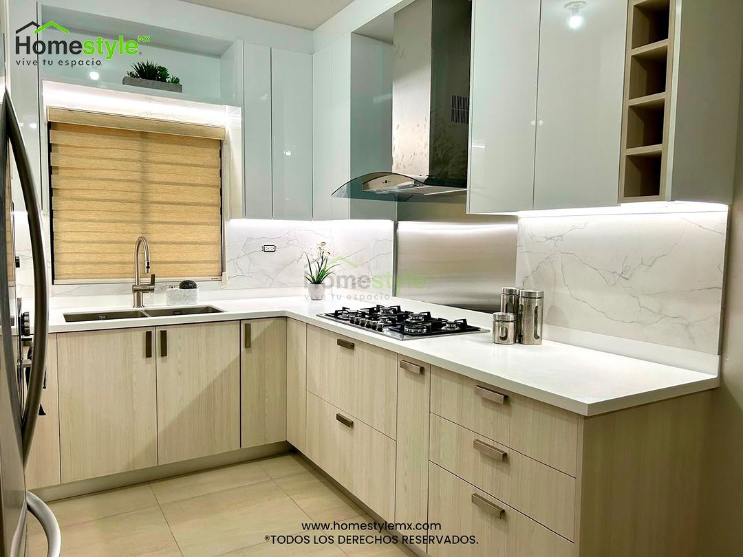 Cocina en forma de U. Diseñada en Melamina Teka Ártico y MDF Alto Brillo Blanco en gabinetes, con una cubierta de Superficie Solida Frosty White. Backsplash en Melamina Marmara. Instalación y venta de iluminación incluida.