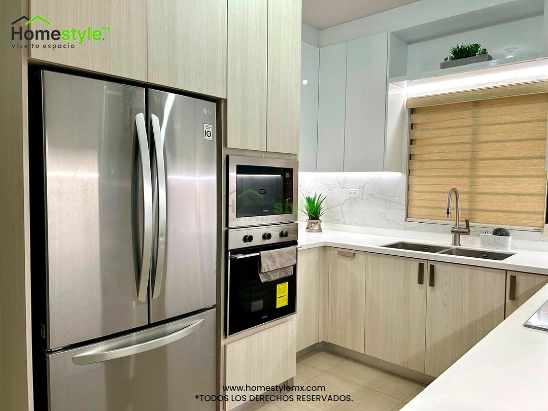 Cocina en forma de U. Diseñada en Melamina Teka Ártico y MDF Alto Brillo Blanco en gabinetes, con una cubierta de Superficie Solida Frosty White. Backsplash en Melamina Marmara. Instalación y venta de iluminación incluida.